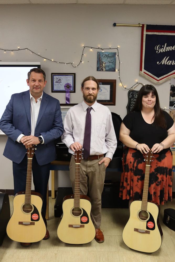 Mr. Putnam, Daniel Hill, and Brittany Koutsunis posing with donated guitars. 